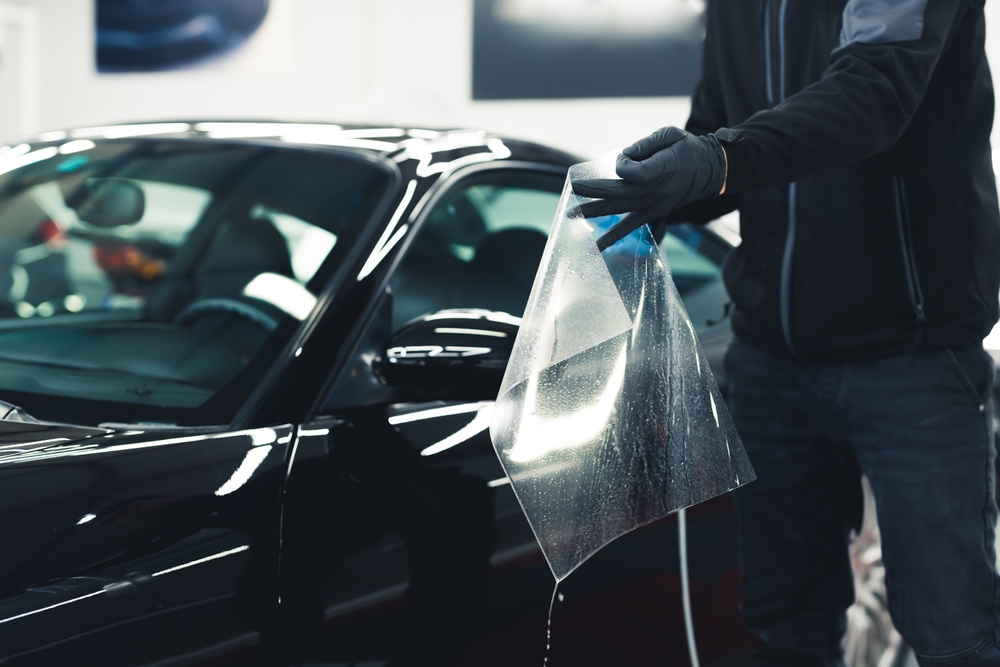 Man wearing black gloves while installing paint protection film